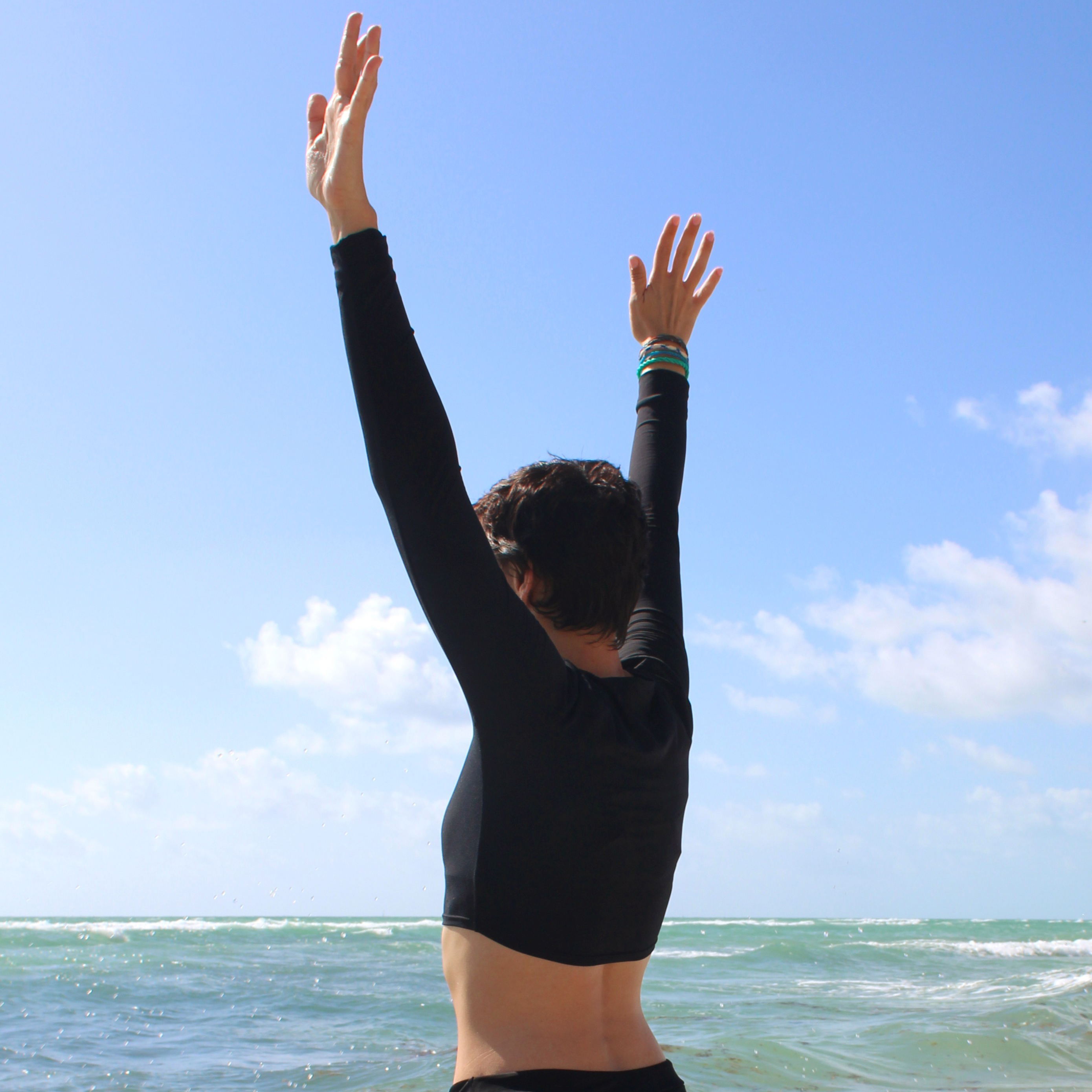 SeaSweepers Women's activewear model wearing a black colored cropped rashguard with hands in the air.